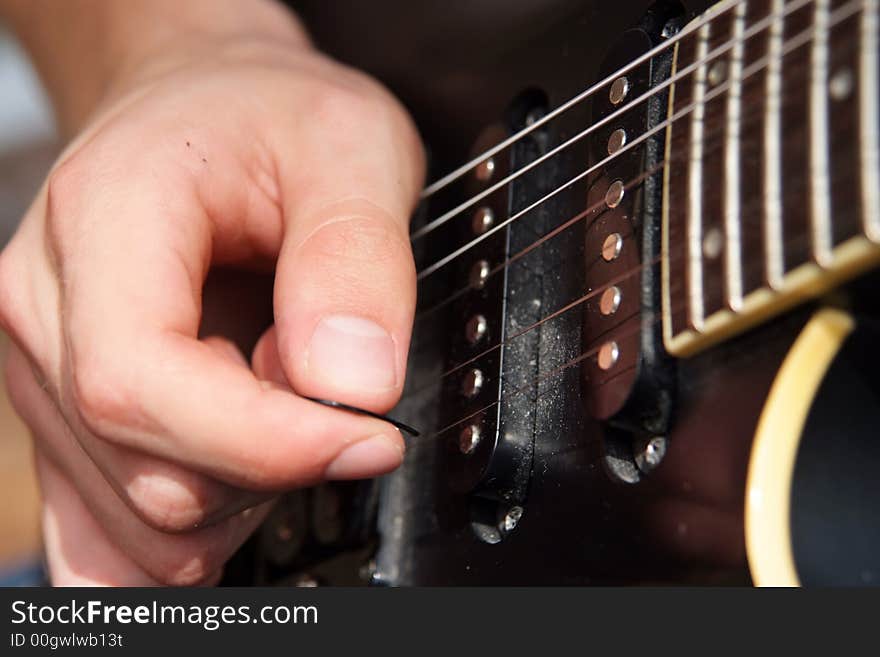 Close up of a hand playing with a pick on an electric guitar. Close up of a hand playing with a pick on an electric guitar