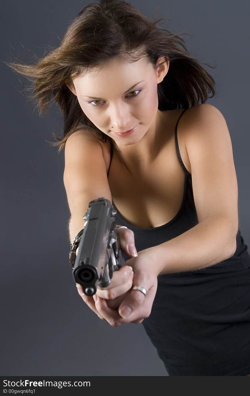 Attractive brunette pointing handgun towards camera. Attractive brunette pointing handgun towards camera