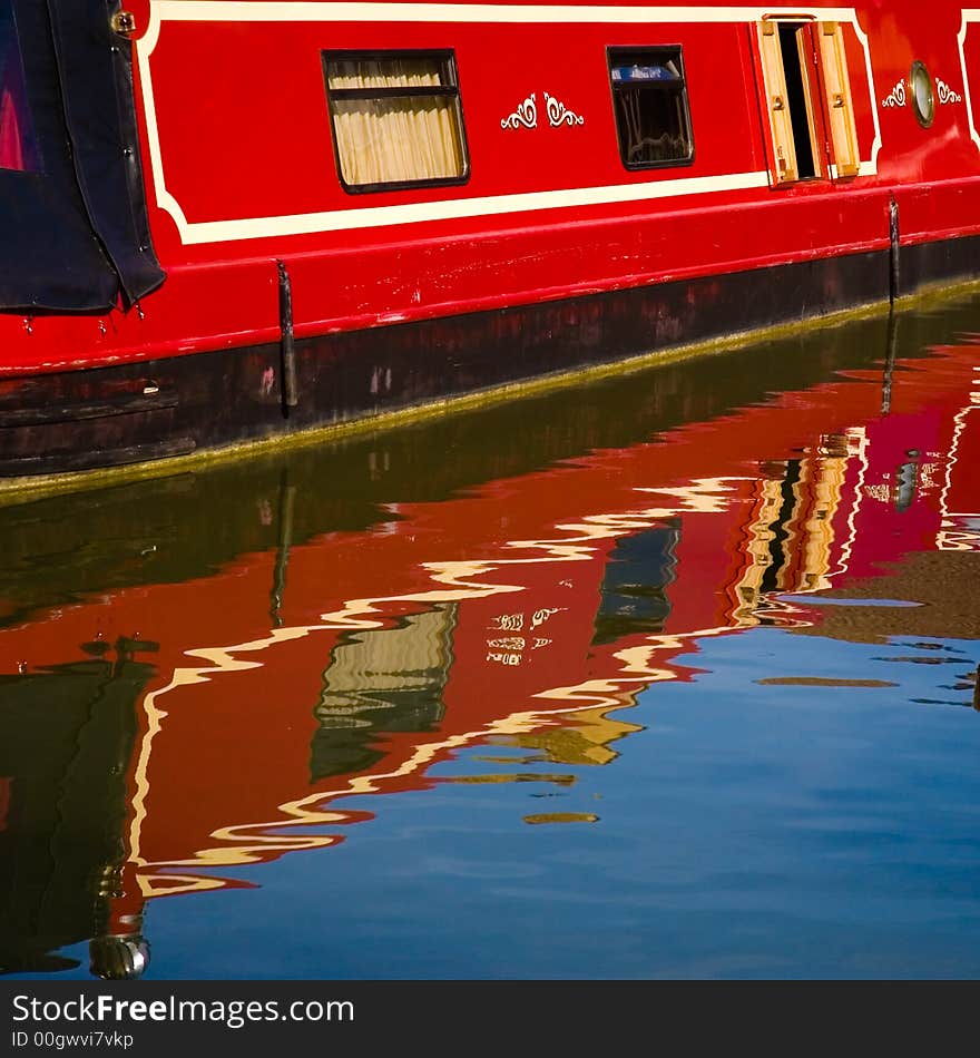 A red barge reflected in the Grand Union  Canal.