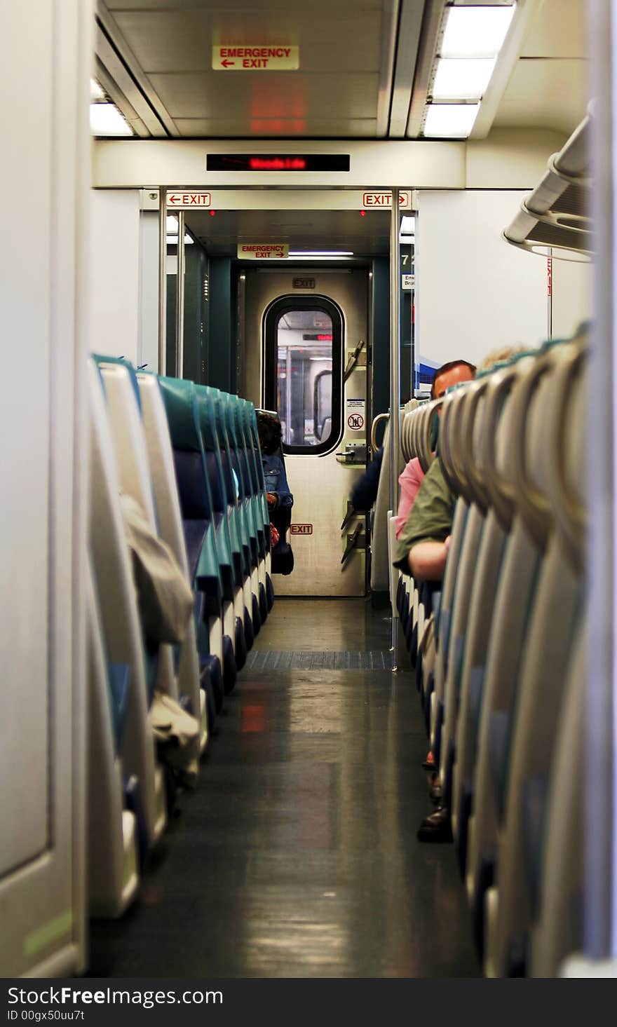 A row of seats and passengers inside a commuter train cabin. A row of seats and passengers inside a commuter train cabin