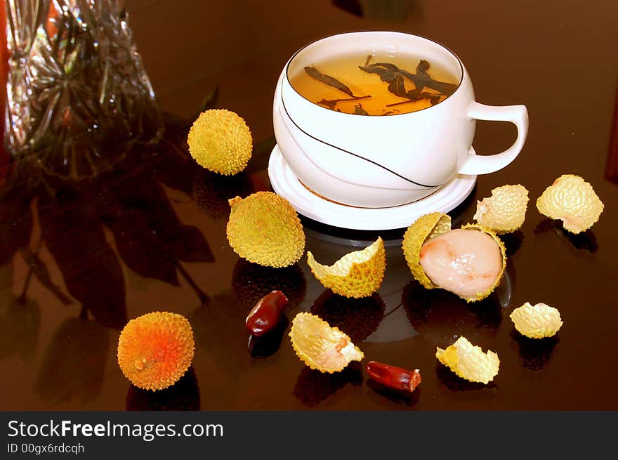 A cup of black tea and some litchi fruits. A cup of black tea and some litchi fruits