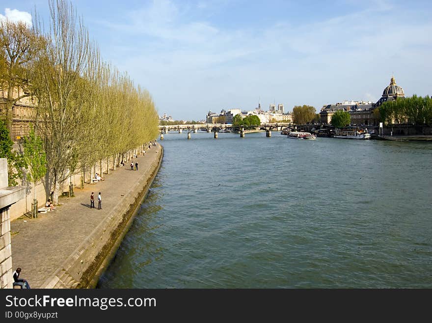 Looking up the Seine River, Paris, France, with houses and buildings lining the river and clouds in the background