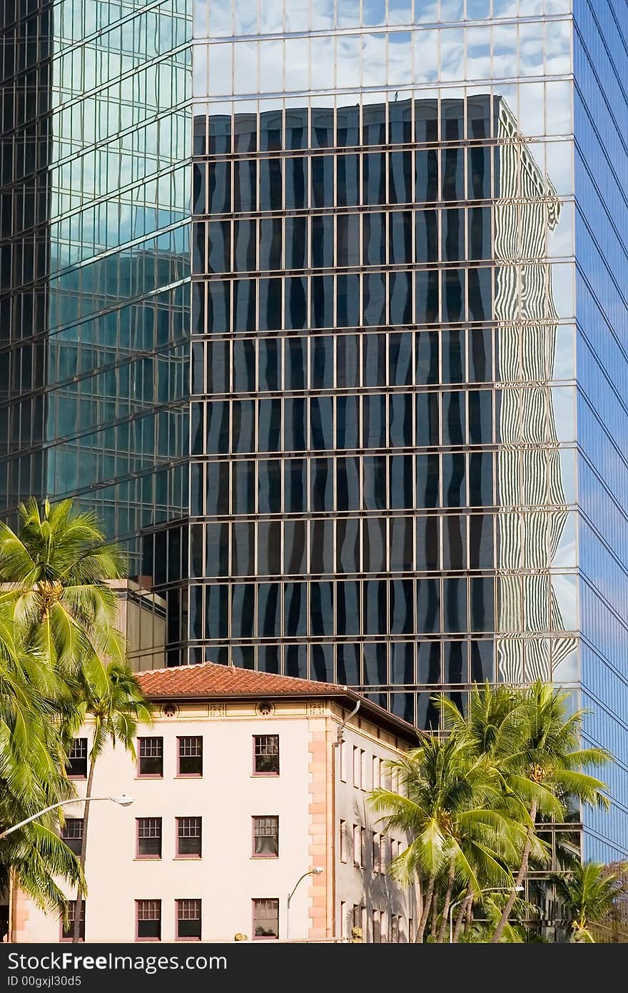 A building reflection of another building while dwarfing a neighboring building. A building reflection of another building while dwarfing a neighboring building