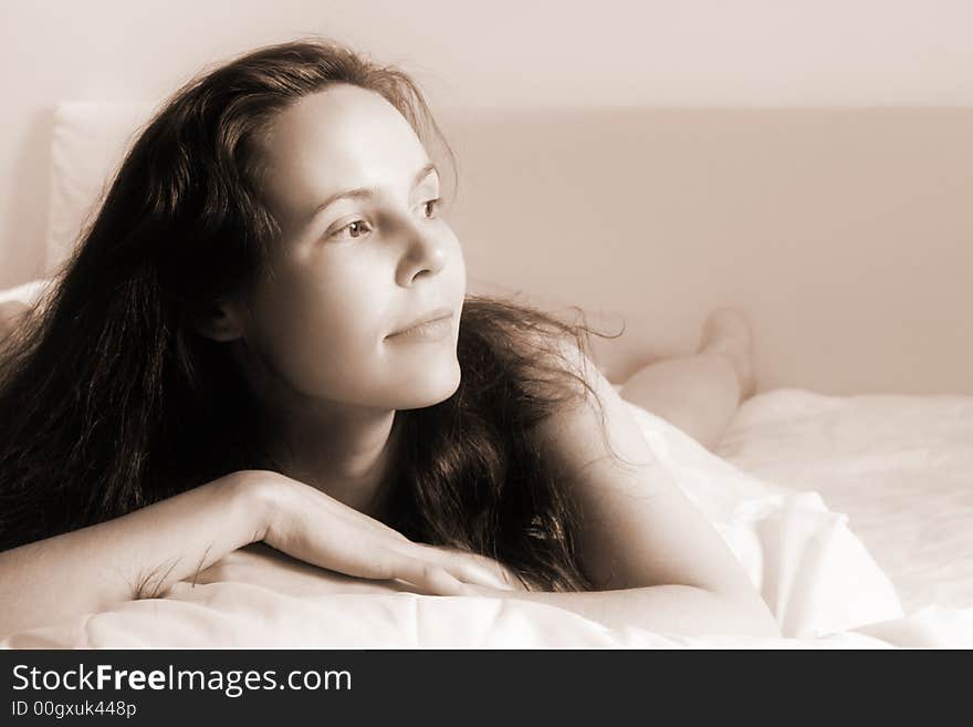 Portrait of a young just awakened woman lying on a bed(soft focused+sepia toned version). Portrait of a young just awakened woman lying on a bed(soft focused+sepia toned version)