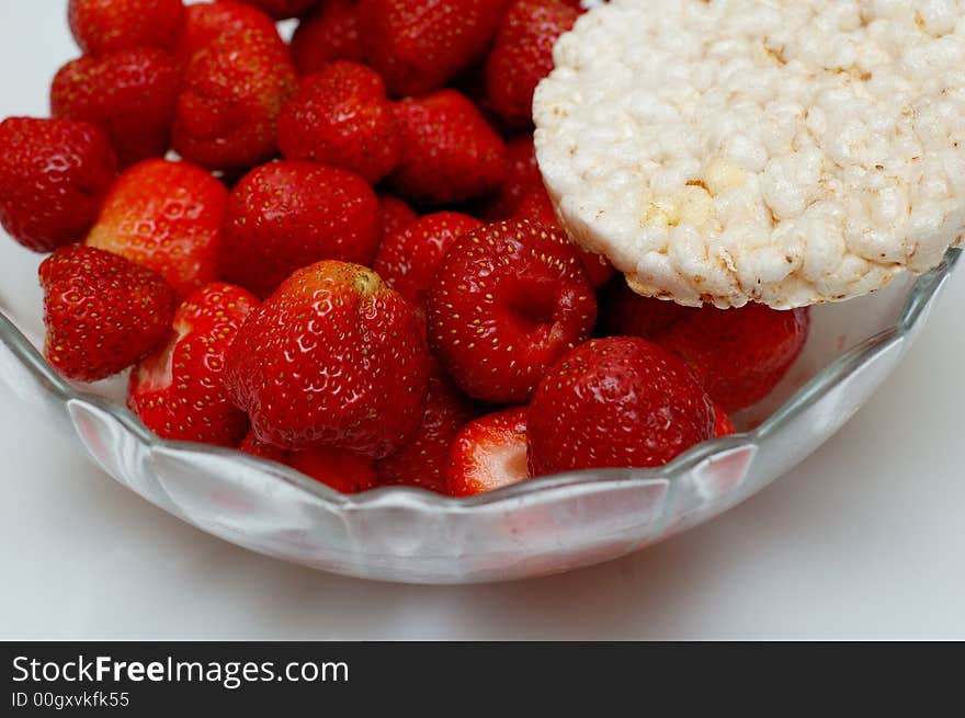 Glass bowl of fresh red strawberries and slice of corn bread. Glass bowl of fresh red strawberries and slice of corn bread.