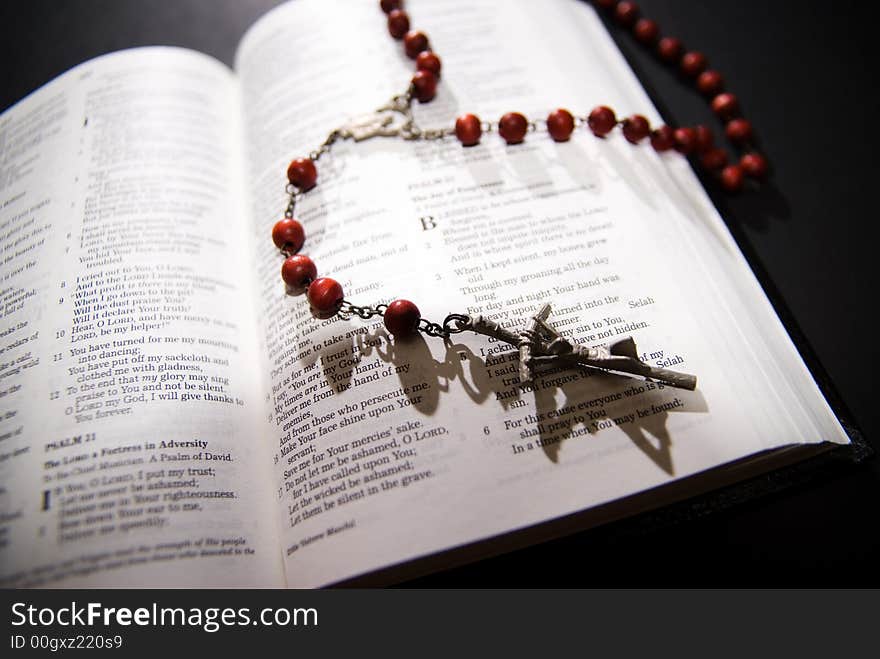 Red rosary and holy bible, shot with dramatic lighting