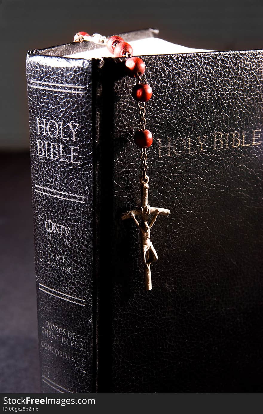 Red rosary and holy bible, shot with dramatic lighting