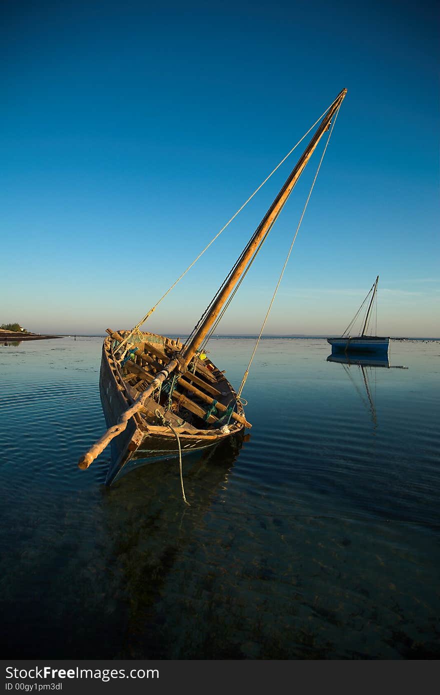 Two dhows waiting in the water during low tide.