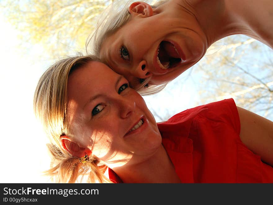 Two sisters have fun together. They are looking down to a dog? a baby?