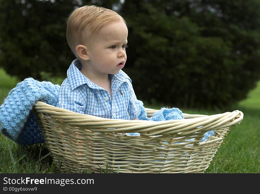 Image of beautiful toddler sitting in a basket in the grass. Image of beautiful toddler sitting in a basket in the grass