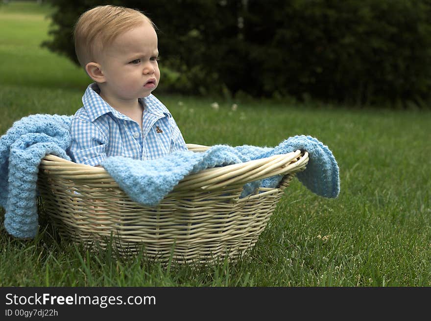 Image of beautiful toddler sitting in a basket in the grass. Image of beautiful toddler sitting in a basket in the grass