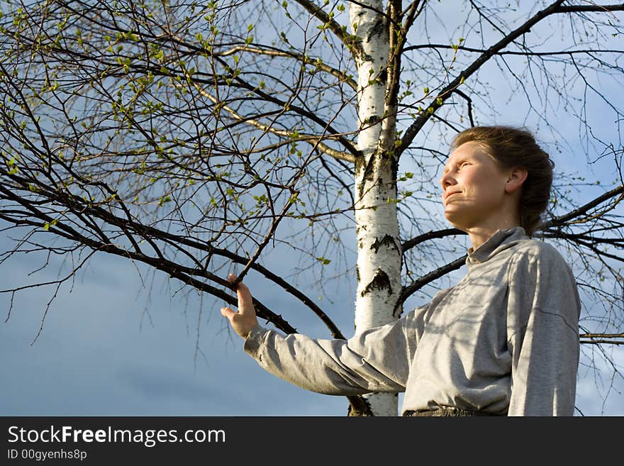 Woman and birch tree with leaves is expanding. Woman and birch tree with leaves is expanding