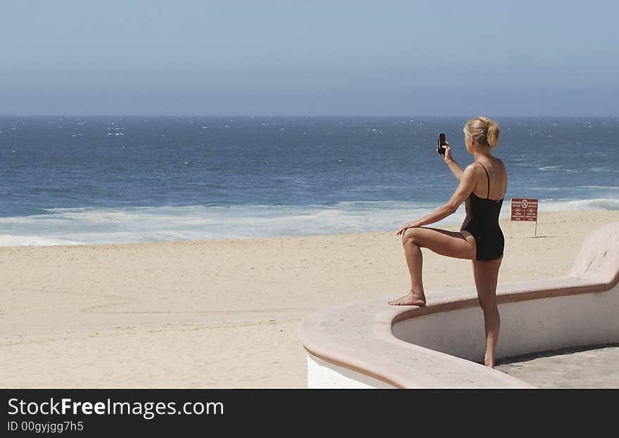 Woman taking a picture with a mobile phone of an empty beach in Cabo San Lucas, Mexico. Woman taking a picture with a mobile phone of an empty beach in Cabo San Lucas, Mexico.