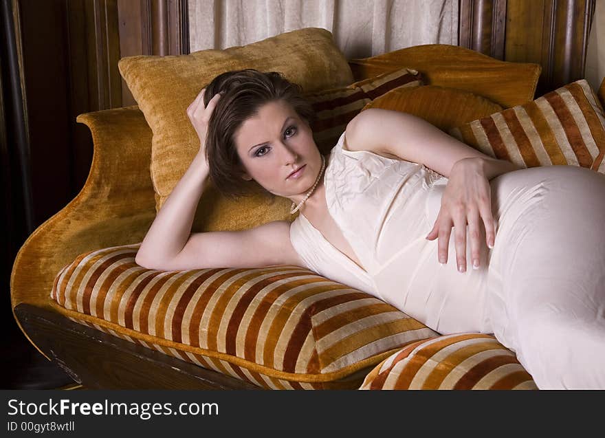 Beautiful young brunette woman wearing a vintage slip reclining on a couch. Beautiful young brunette woman wearing a vintage slip reclining on a couch.