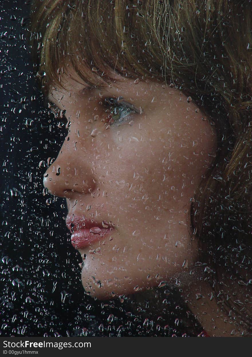 Girl looks thru waterdropped widow glass in rainy weather. Girl looks thru waterdropped widow glass in rainy weather