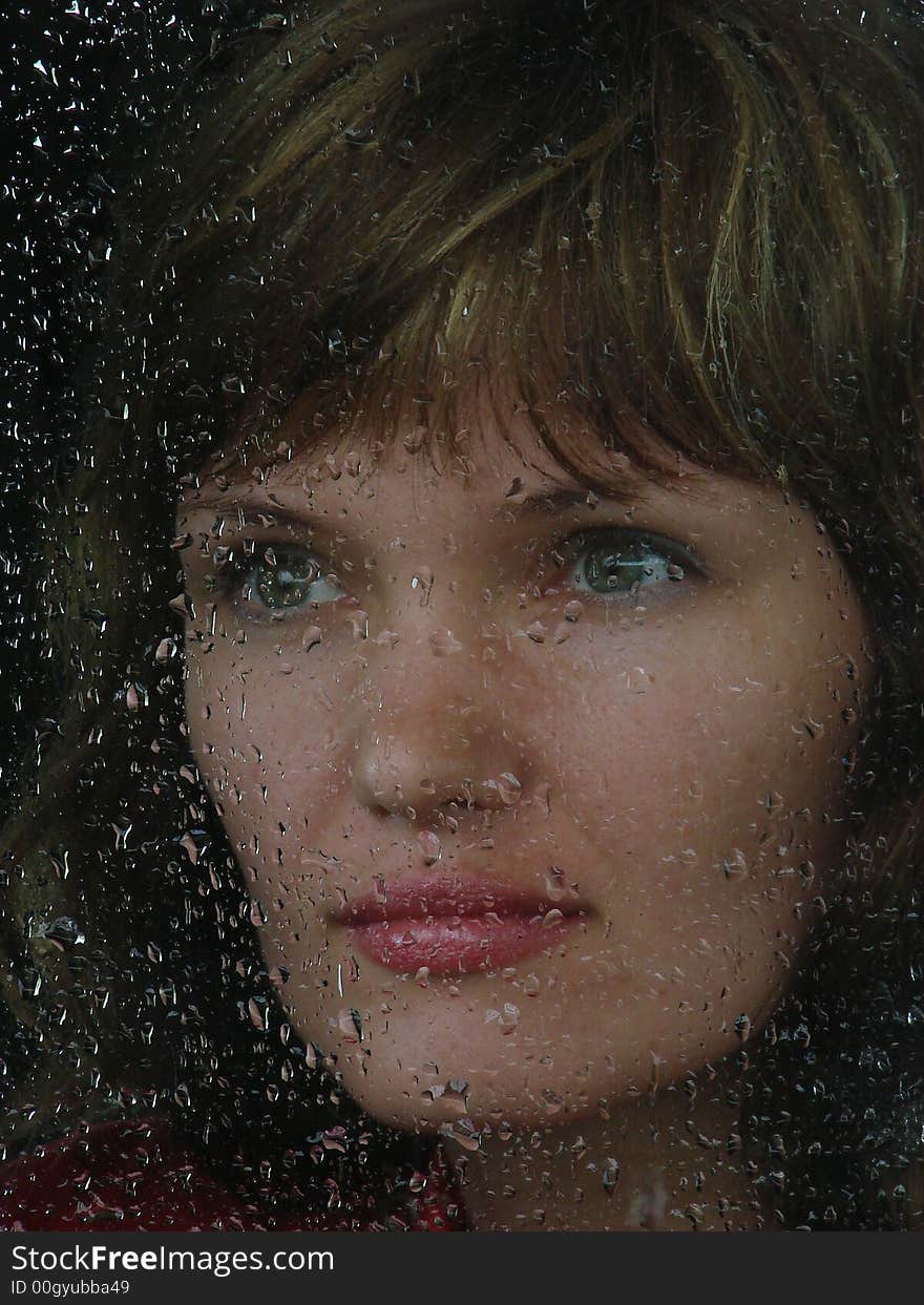 Girl looks thru waterdropped widow glass in rainy weather. Girl looks thru waterdropped widow glass in rainy weather