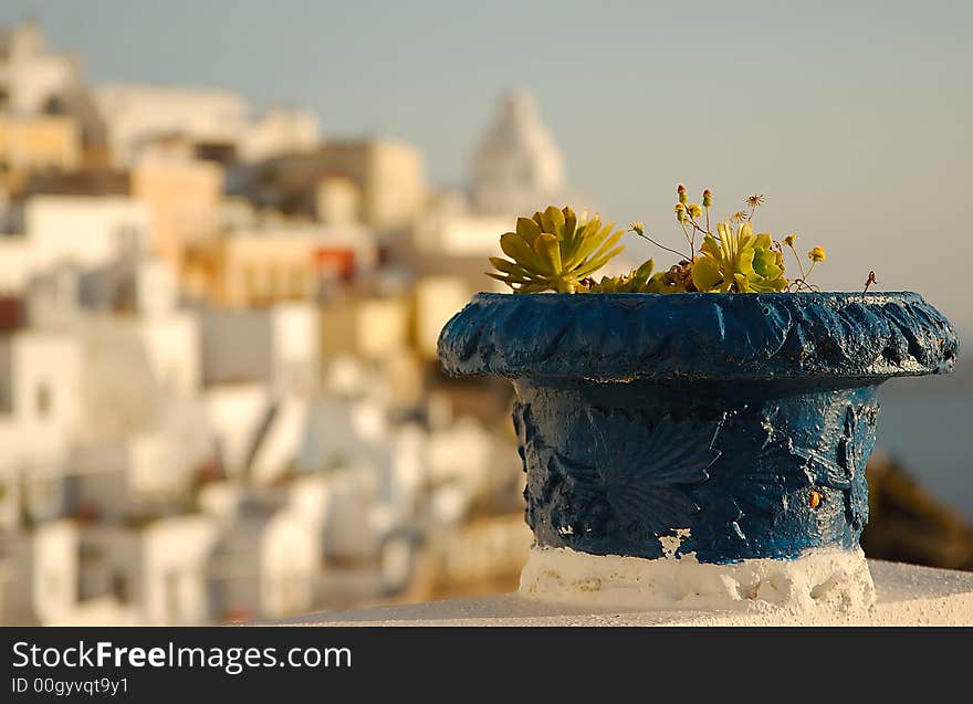 Blue plant pot on the island of Santorini, Greece. The town of Fira appears in the background. Blue plant pot on the island of Santorini, Greece. The town of Fira appears in the background