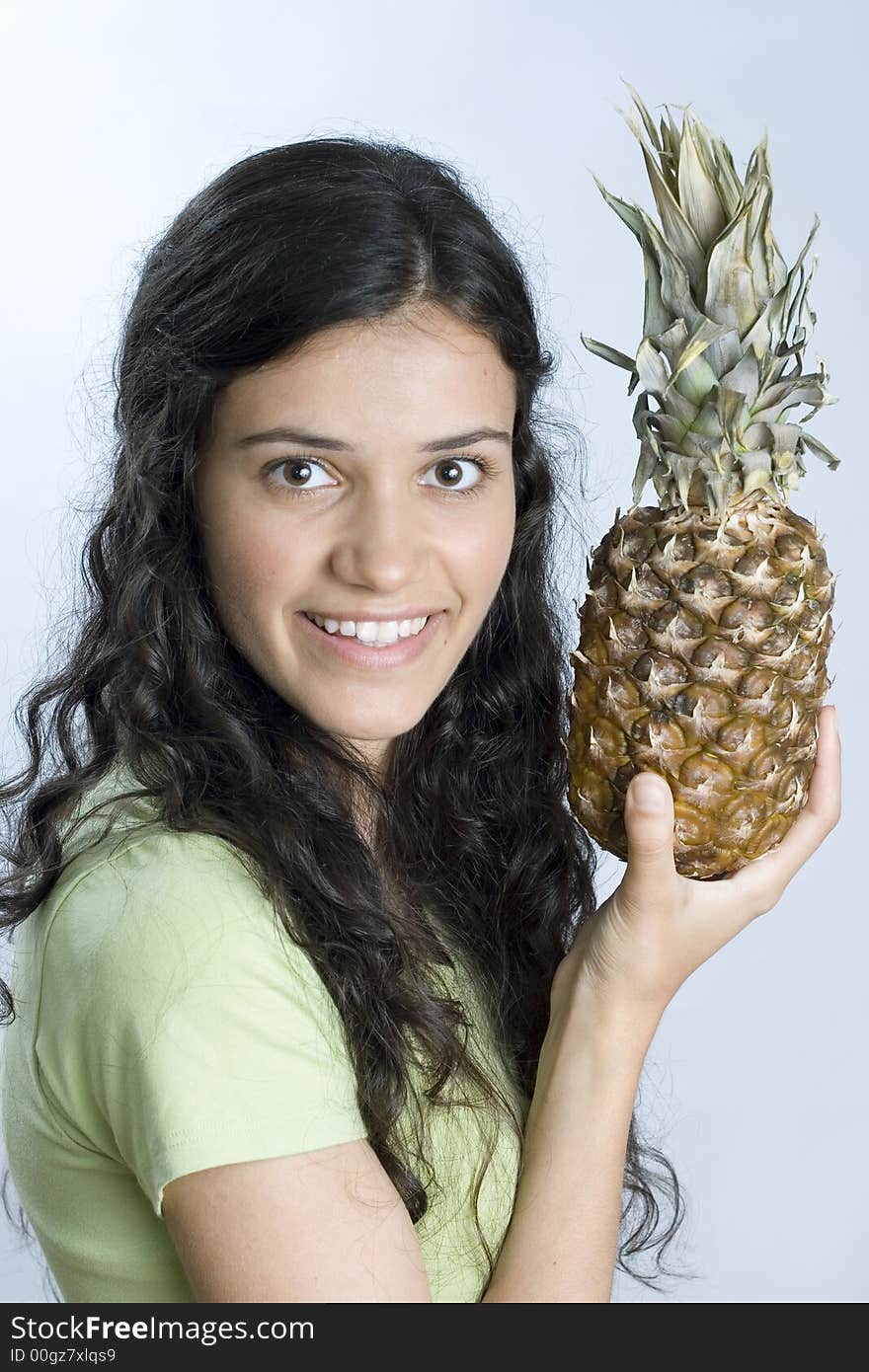 Smiling girl in green holding pineapple. Smiling girl in green holding pineapple