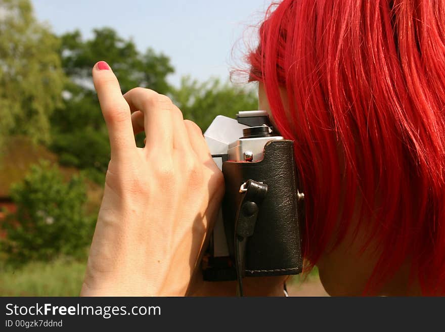 Pink fingernail on red haired photographer with camera taking pictures in nature. Pink fingernail on red haired photographer with camera taking pictures in nature