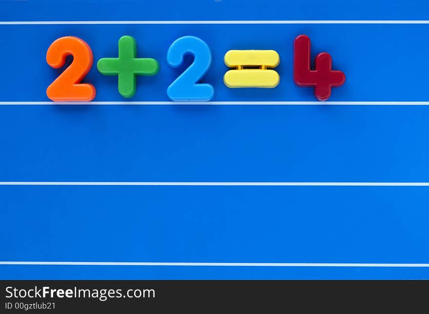 A simple sum, from a child's toy number set, placed on a blue, lined background. Space for text elsewhere in the image. A simple sum, from a child's toy number set, placed on a blue, lined background. Space for text elsewhere in the image.