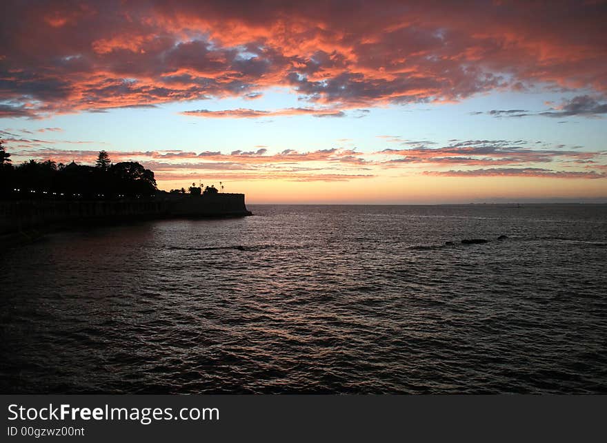 Sunset over the sea with old castle and clouds. Sunset over the sea with old castle and clouds