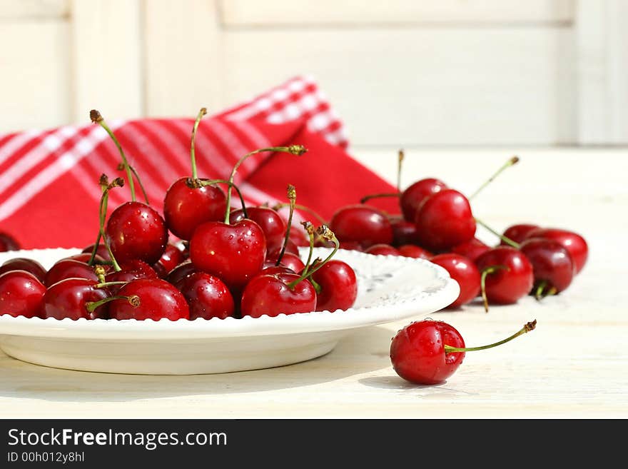 Red cherries on a plate with white shutters