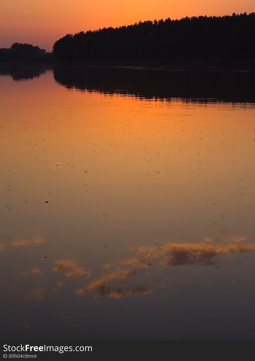 Sunset, quiet lake over blue-orange sky