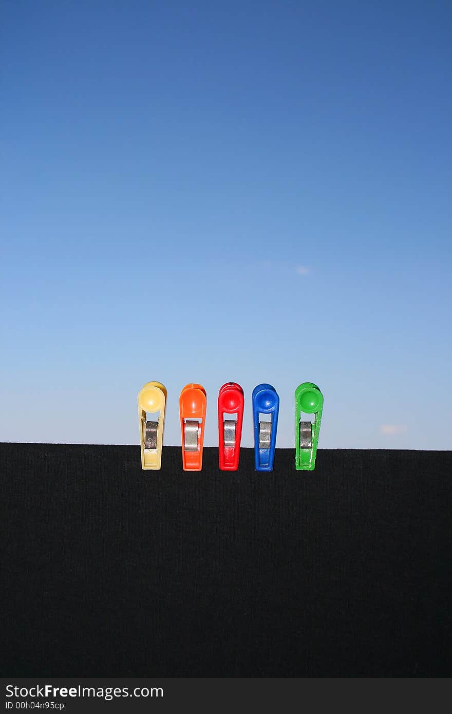 Clothespins on a black shirt with clear blue sky in the background. Clothespins on a black shirt with clear blue sky in the background