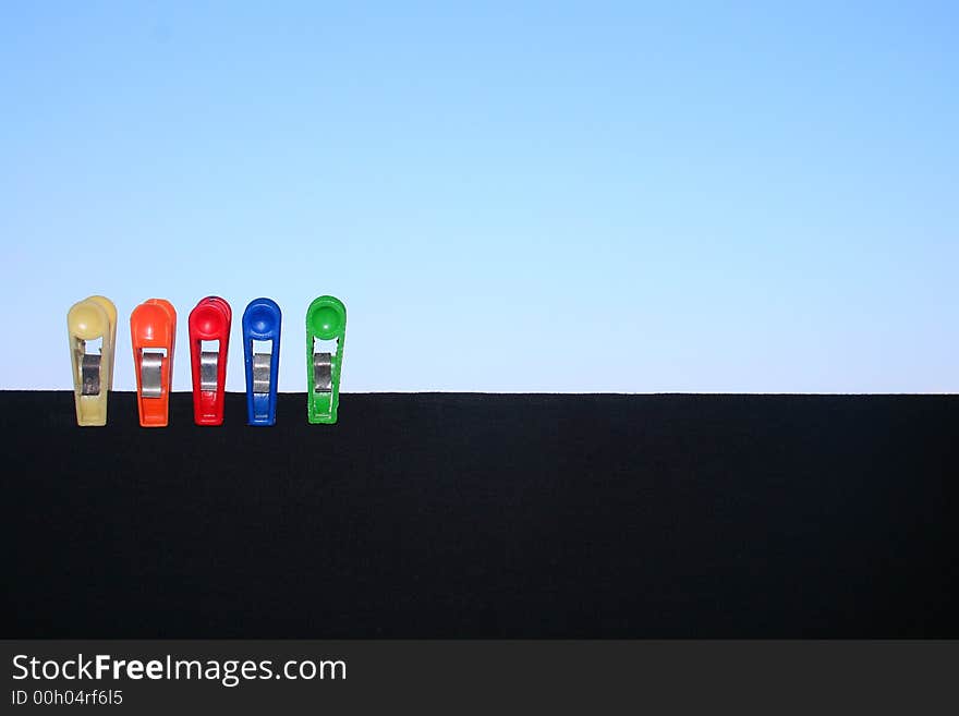 Clothespins on a black shirt with clear blue sky in the background. Clothespins on a black shirt with clear blue sky in the background