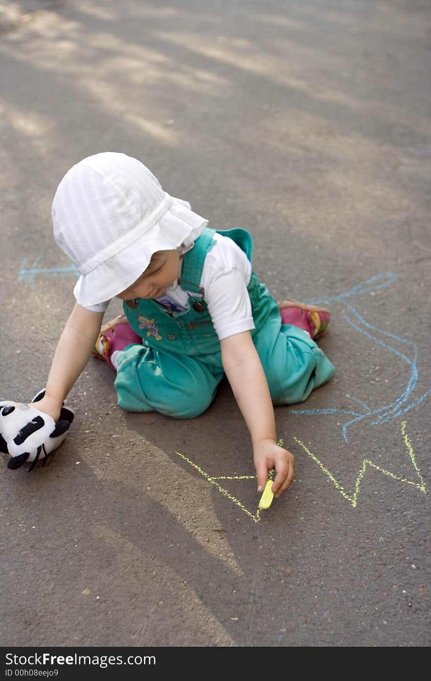 Baby drawing chalk on asphalt lettesr ma