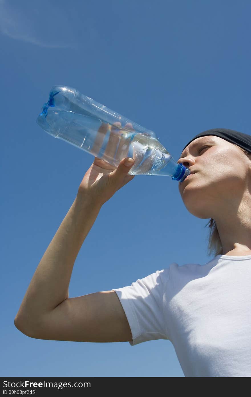 Sporty woman have water from bottle over blue sky