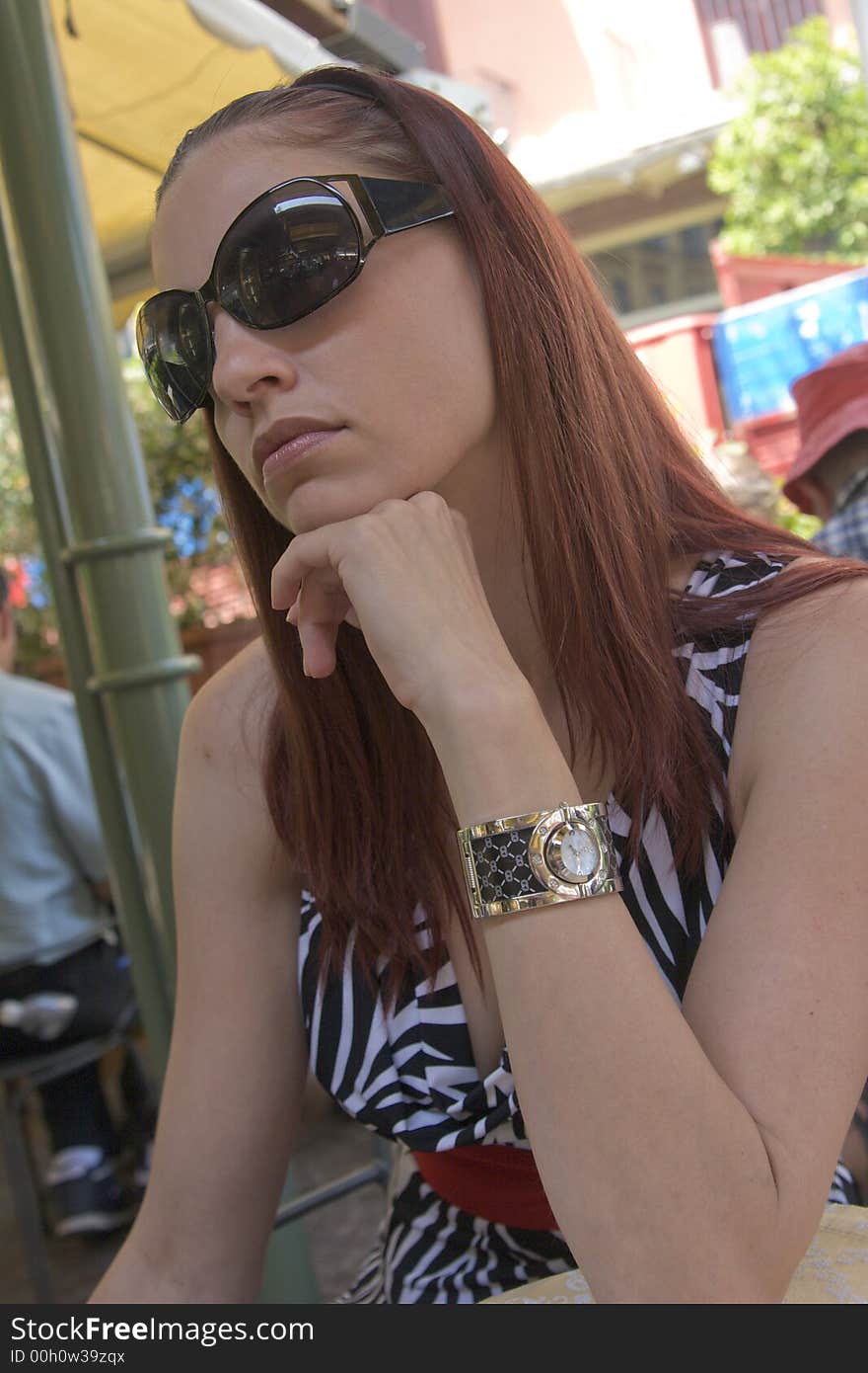 Beautiful young woman looking bored in a sidewalk cafe in Sorrento, Italy.