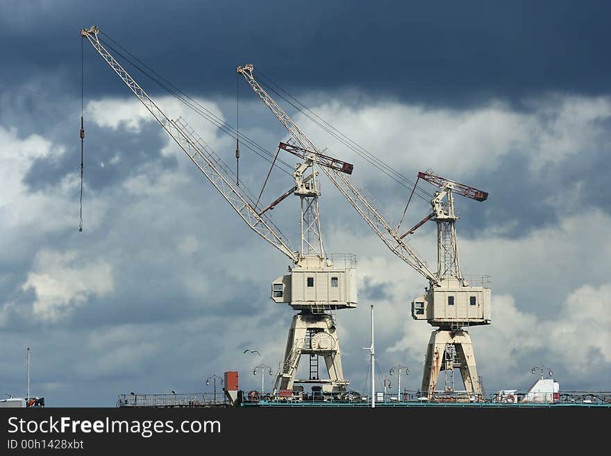 Two cranes in a port with a stormy sky in the background. Two cranes in a port with a stormy sky in the background