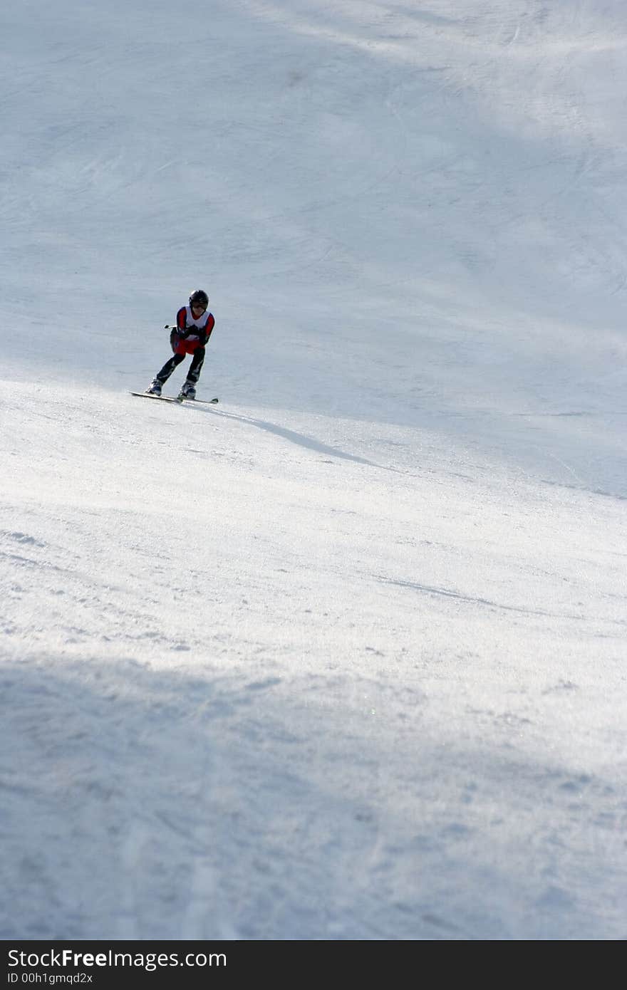 Alpine racer skiing downhill in a tuck