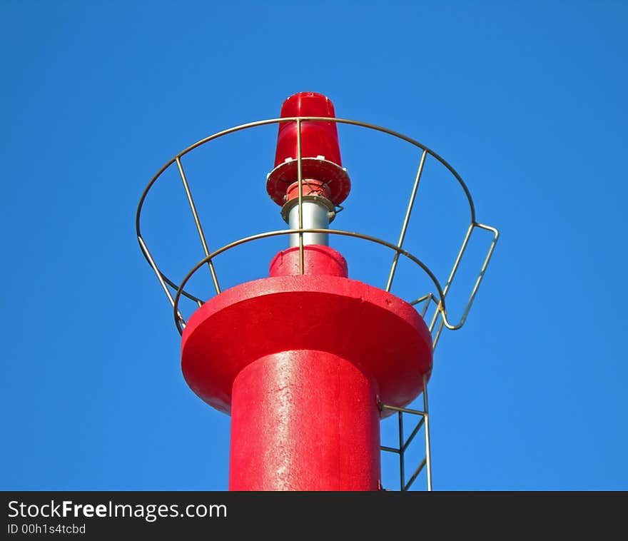 Brilliant red lighthouse against clear blue sky