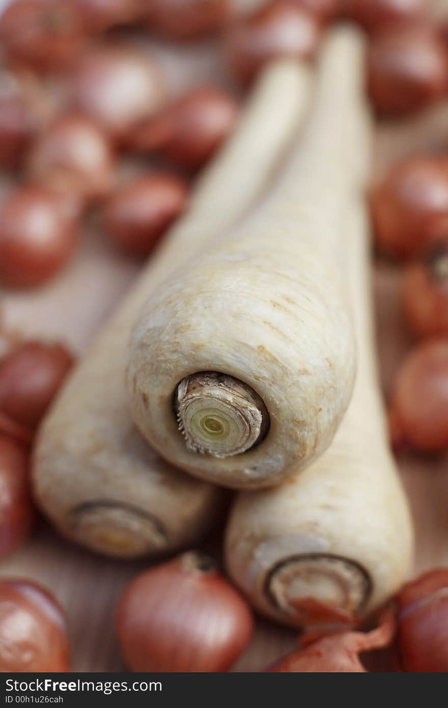 Fresh organic parsnips and shallots on chopping board