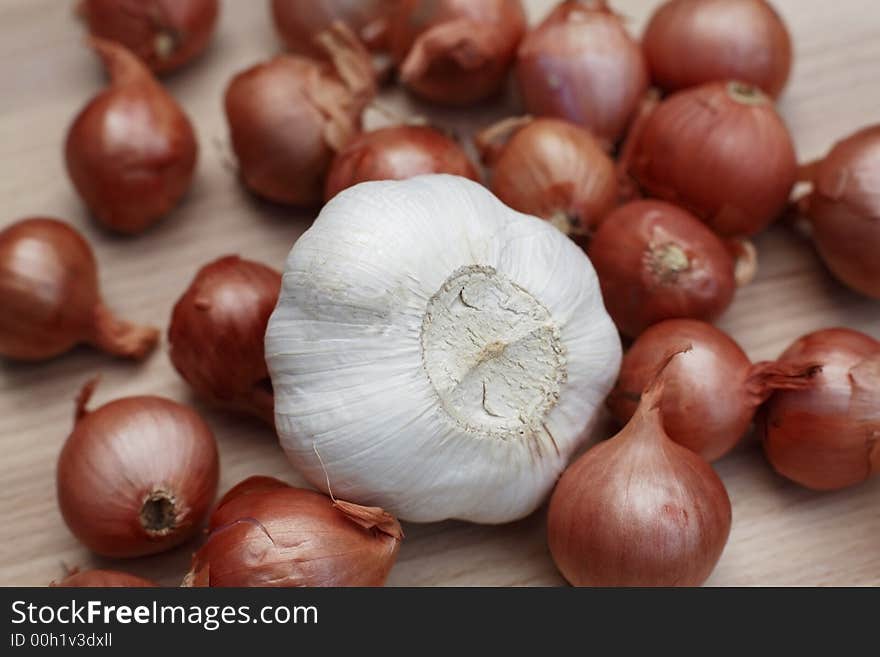 Fresh shallots and whole garlic on chopping board. Fresh shallots and whole garlic on chopping board