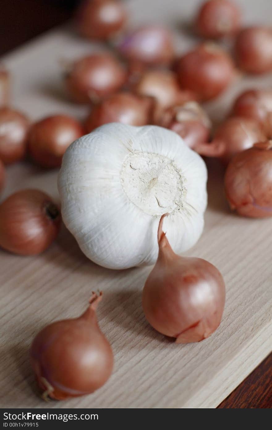 Fresh shallots and whole garlic on chopping board. Fresh shallots and whole garlic on chopping board