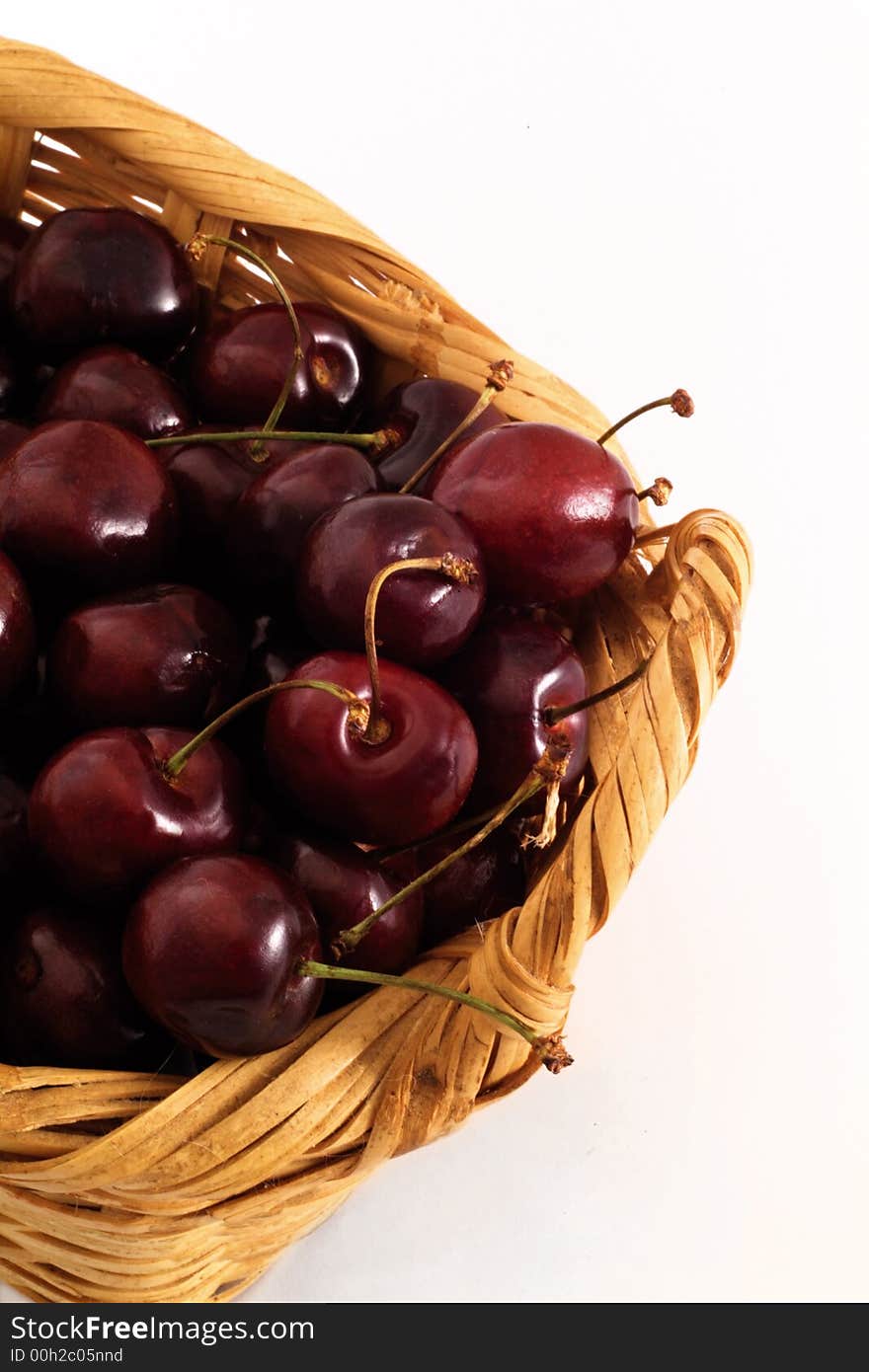 A handmade basket with delicious red ripe cherries, isolated in a white background in studio conditions. A handmade basket with delicious red ripe cherries, isolated in a white background in studio conditions.