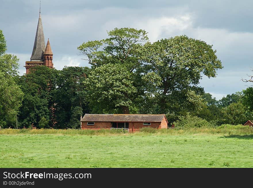 Rundown old building being used as a cowshed in the countryside with a church spire in the background. Rundown old building being used as a cowshed in the countryside with a church spire in the background.