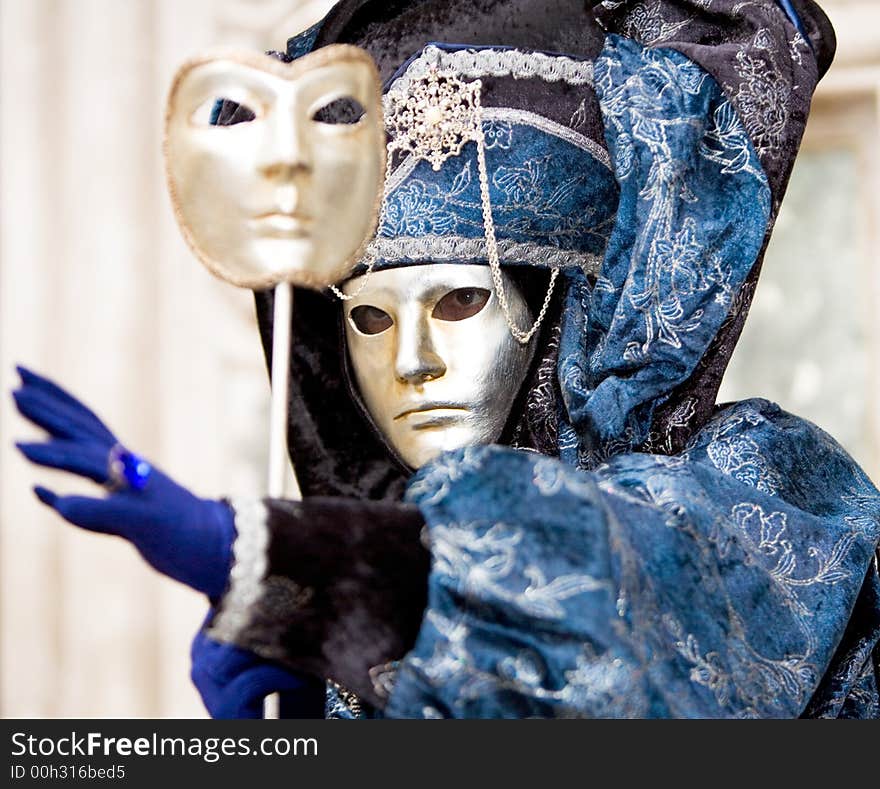 A man in a golden mask and blue costume at the Venice Carnival