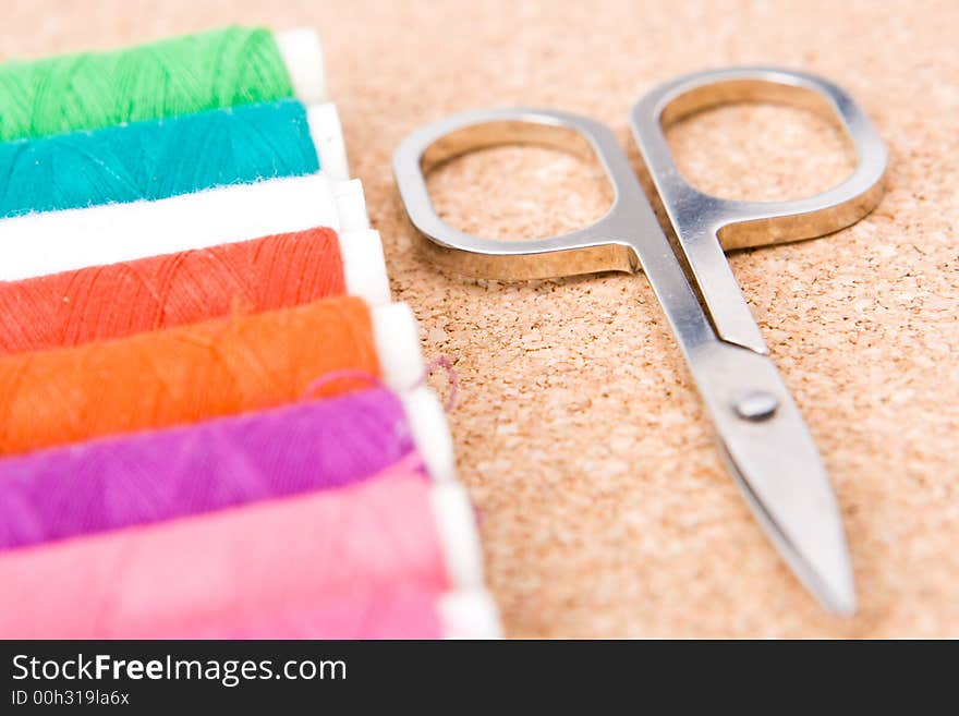 Rolls of colorful cotton with selective  focus on the scissors