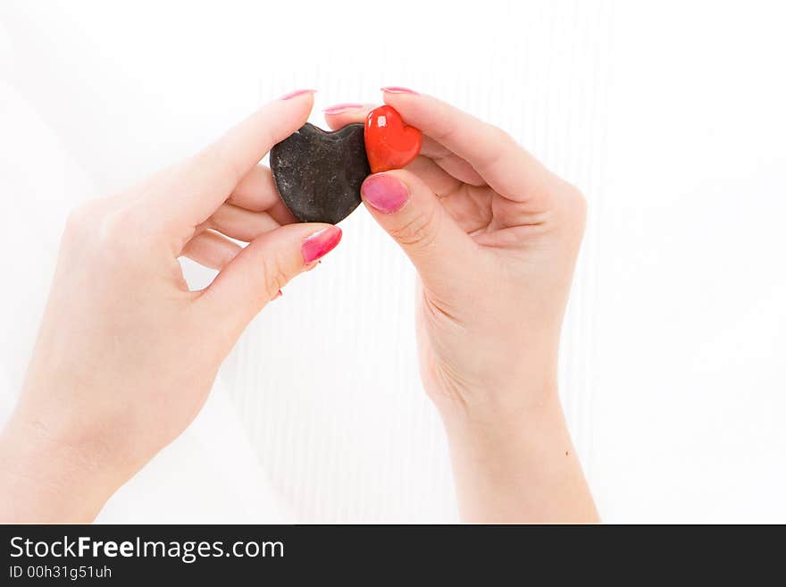 Hands holding red and black stone hearts. Hands holding red and black stone hearts