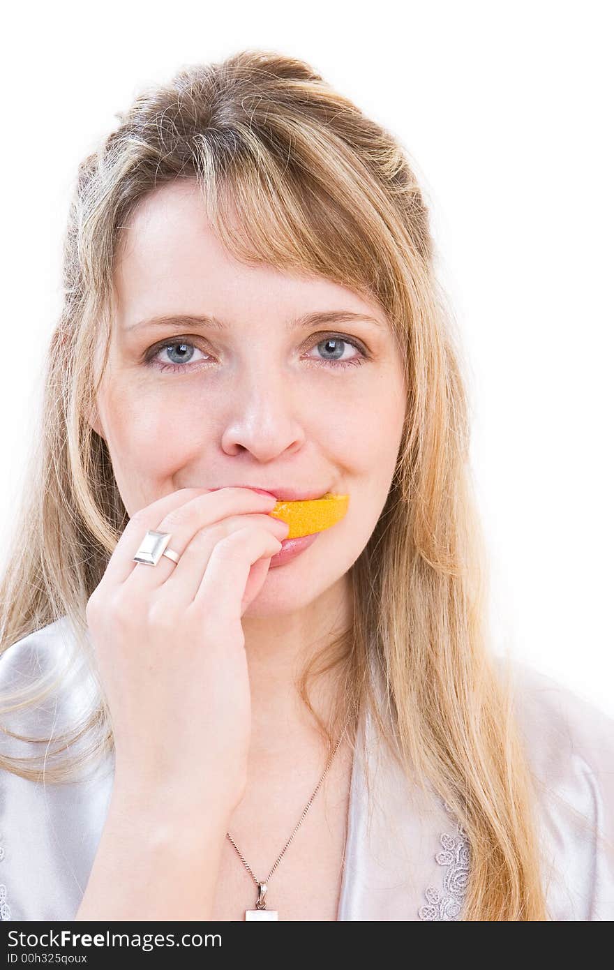 A woman in a silver robe biting a segment of orange