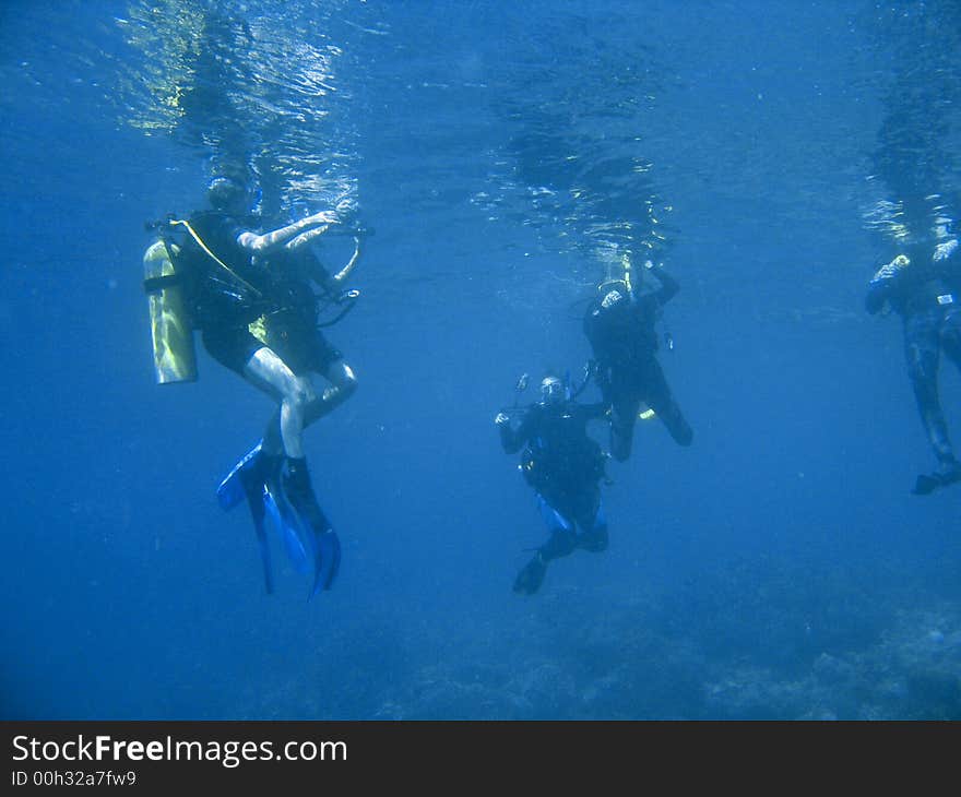 Scuba divers exploring a pristine tropical coral reef under water during dive class. Scuba divers exploring a pristine tropical coral reef under water during dive class