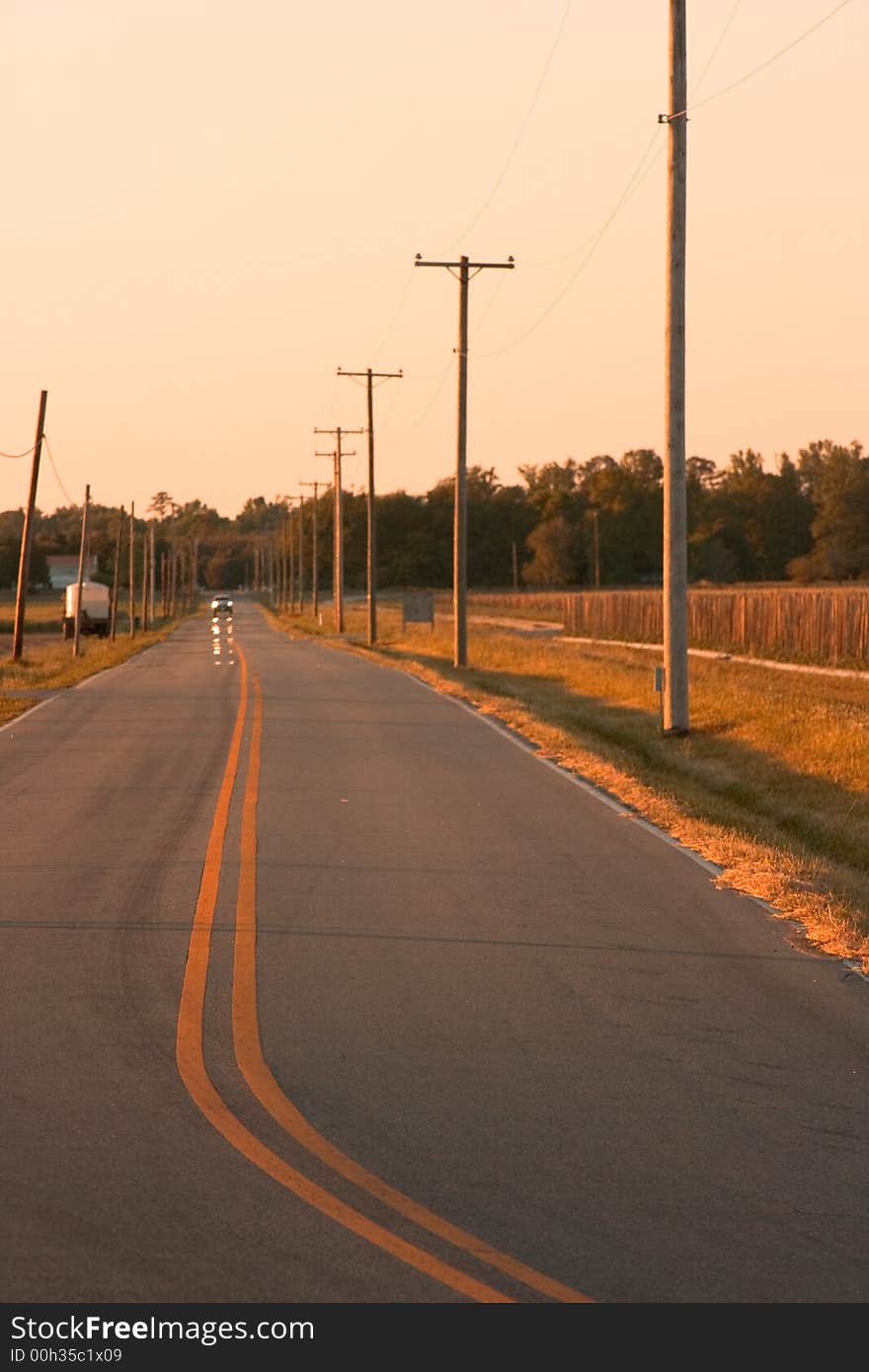 Lonely open country road with pickup truck with golden light