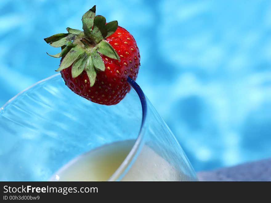 Cocktail with strawberry standing by the poolside. Cocktail with strawberry standing by the poolside