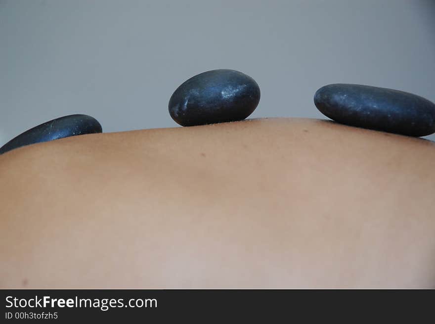 Hot stones relax massage. Girl's back with three hot stones.