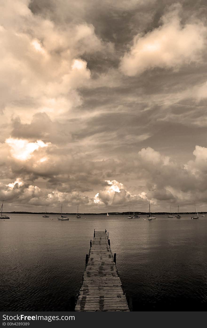 Dock floating in lake with sky and sailboats. Dock floating in lake with sky and sailboats