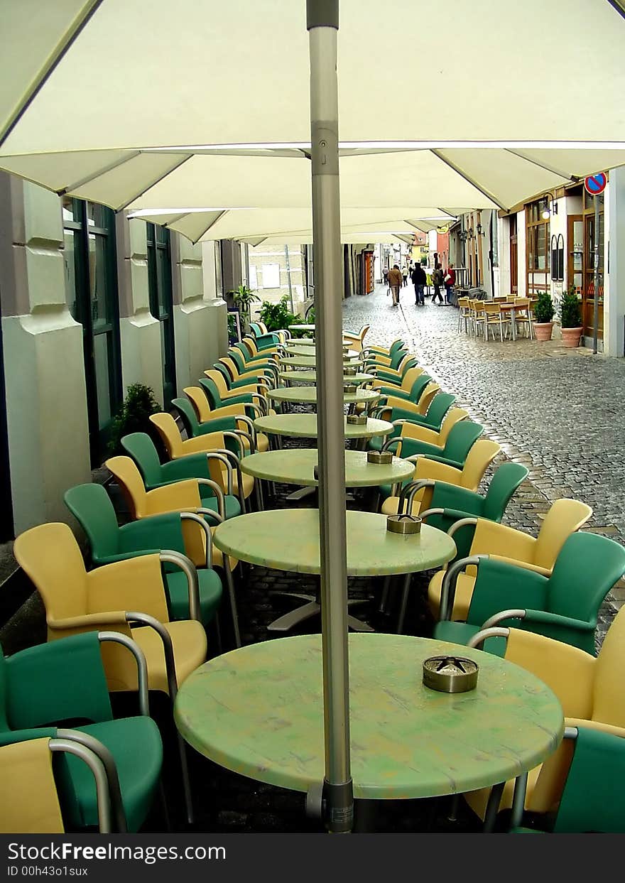 Chairs, tables and parasolars of a cafe in a row.